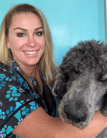 smiling blond female with black haired poodle